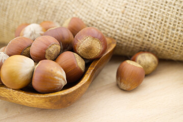 Hazelnuts beside the jute sack on wooden table