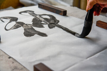 An old Chinese calligrapher is writing brush characters, creating Chinese calligraphy...