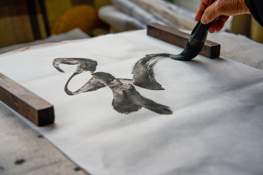 An old Chinese calligrapher is writing brush characters, creating Chinese calligraphy works.
Translation: Spring comes, the god of wind arrives.