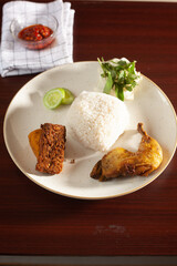 Indonesian Fried Chicken served with tofu, tempe, tomatos, cucumber and rice.