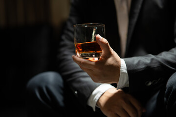 Businessman sitting Holding a Glass of Whiskey Drink Whiskey in the liquor store room