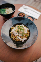 Mie ayam (noodles with chicken, meatballs, dumplings and vegetables) is a popular street food in Indonesia. Blurred background. Close up. Selective focus