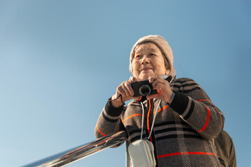 Senior Chinese tourist holding a camera in hand on cruise ship on Saint Lawrence river. Thousand...
