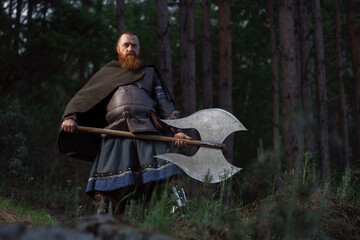 Fantasy medieval red-haired gnome warrior with beard with huge ax halberd in forest - 615310098