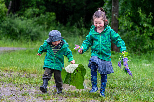 Happy Children Playing In A Puddle In The Rain