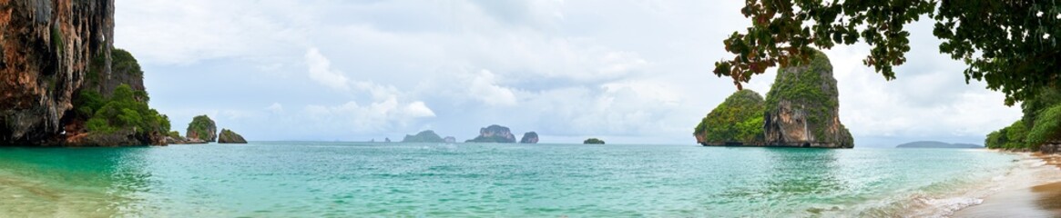 panoramic photo of Railey beach, Krabi, Thailand.Turquoise blue and emerald green ocean with rocky mountains covered with green trees. in the background you can see the turtle mountain. 