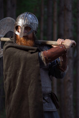 Naklejka premium Fantasy medieval red-haired gnome warrior with beard with huge ax halberd in forest