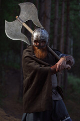 Fototapeta premium Fantasy medieval red-haired gnome warrior with beard with huge ax halberd in forest