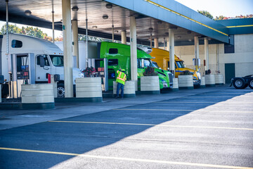 Pro industrial big rigs semi trucks with semi trailers refuel tanks stand at truck stop gas station