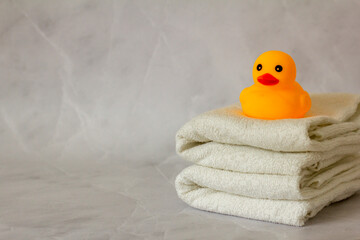 A yellow rubber duck for bathing on a stack of clean white towels.