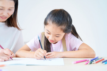 部屋でお絵描きをして遊ぶ親子