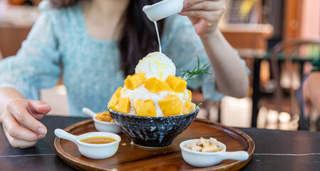 Shaved ice dessert with mango slices. Served with vanilla ice cream and whipped cream. Sweet dessert in Korean style. Local name, Bingsu. - obrazy, fototapety, plakaty