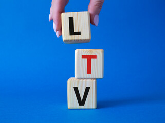 LTV - Life Time Value symbol. Concept word LTV on wooden cubes. Businessman hand. Beautiful blue background. Business and LTV concept. Copy space.