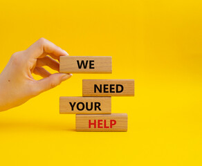 We need your help symbol. Wooden blocks with words We need your help. Beautiful yellow background. Businessman hand. Business and We need your help concept. Copy space.