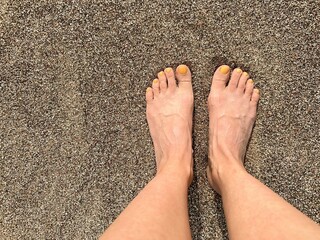 The girl put her feet together on the sand in a golden sunset