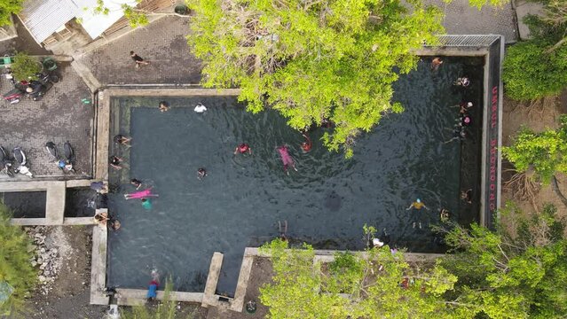 Aerial view of people in natural swimming pool in the midle of forest in Klaten, Indonesia
