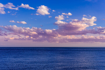 scenic blue seascape of sunset or sunrise above water with beautiful colorful evening clouds