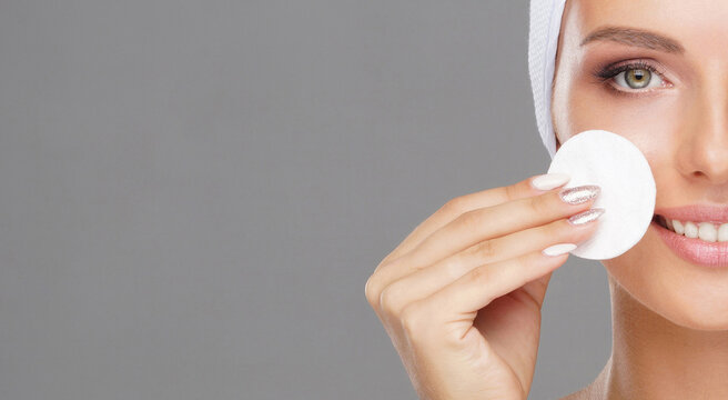 Young woman cleaning her face with a cotton pads. Girl removing cosmetics with hygienic discs.