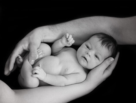 black and white photo of newborn baby being held by parents