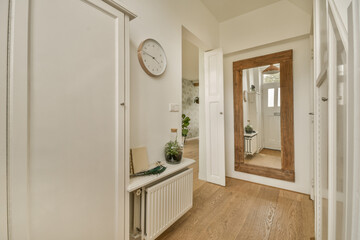 a hallway with wood flooring and a clock hanging on the wall above the door to the entranceway area