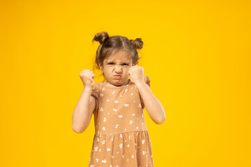 Angry little girl on a yellow background