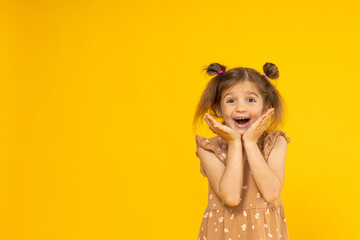 Happy little girl on a yellow background, place for text