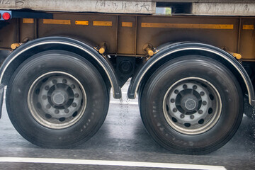 Detail of the wheels of a truck driving on the road in the rain.