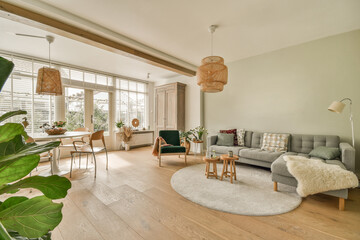 a living room with wood flooring and large plants in the center of the room there is a couch,...