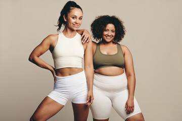 Healthy lifestyle on display: Two young women standing proud in sporty fitness clothes