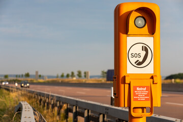 Highway Safety: Orange SOS Calling Box on German Highway amidst Blurry Car, 
