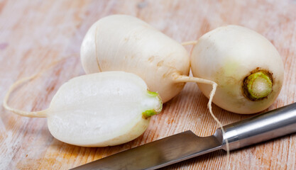 Whole and cut in half ripe turnips root crops on wooden background. Healthy nutrition concept