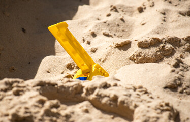 children's plastic toys on yellow sand