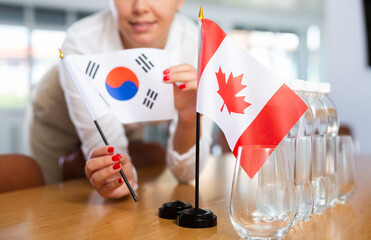 Little flag of Canada on table with bottles of water and flag of South Korea put next to it by...