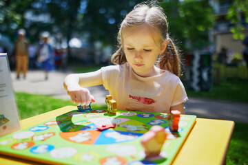 Adorable preschooler girl playing board game