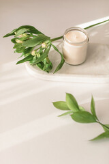 Aesthetic minimal still life with marble tray, candle in glass, alstroemeria flower on white background with beautiful soft shadows. Copy space. Beauty treatments concept.
