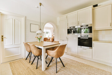 a dining room with two chairs and a table in front of an oven on the other side of the room