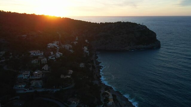 Dramatic tropical summer sunset aerial drone shot on Spanish island Mallorca, Soller with lighthouse and ocean