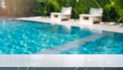 Fototapeta na wymiar Empty white marble stone table top and blurred swimming pool in tropical resort in summer banner background - can used for display or montage your products.