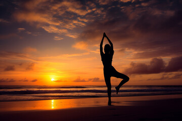 Silhouette of woman doing yoga at beach during sunset. 