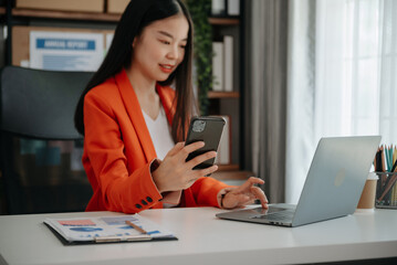 Asian young businesswoman working in the office with working notepad, tablet and laptop documents