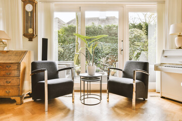 a living room with two chairs and a piano in front of a window that looks out onto the trees outside