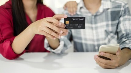 E-commerce Concept. Happy couple holding credit and using smartphone enter their card number in the mobile phone app to purchase and payment in internet store