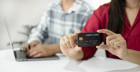 E-commerce Concept. Happy couple holding credit card enjoying doing online shopping and using laptop enter their card number in-app to purchase and payment in internet store