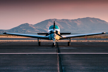 Small general aviation propeller plane parked on an airport in the desert. Photographed during sunrise. 
