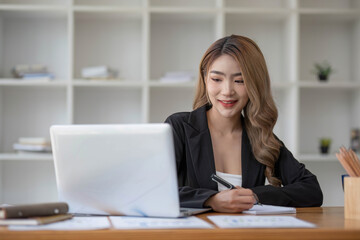 Fototapeta na wymiar young asian woman sitting and taking note at house. Happy smiling working online, Freelance work at home