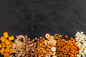 Mix of snacks - pretzels nuts chips top view. Fast food background