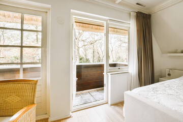 a bedroom with a bed, chair and large window looking out onto the trees outside in the photo is taken from inside