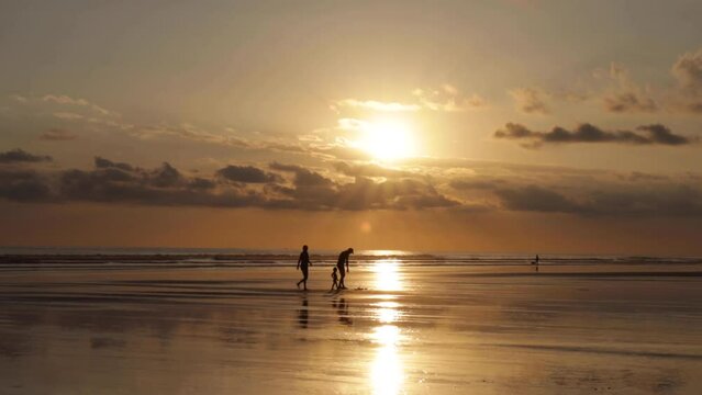 Silhouette of family of three walking out of the beach during the sunset, golden hour in Bejuco Beach, Costa Rica
