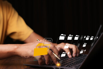 Document Management System (DMS) being setup by IT consultant working on laptop computer in office with document directory. Software for archiving, searching and managing corporate file information