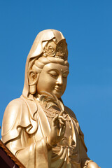 Fototapeta na wymiar Statue of Guan Yin against blue sky